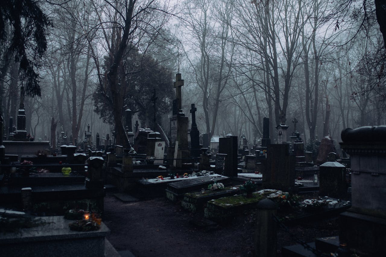 Eerie winter cemetery scene with fog and numerous gravestones and crosses.